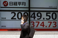 A man wearing a face mask to help curb the spread of the coronavirus walks past an electronic stock board showing Japan's Nikkei 225 index at a securities firm in Tokyo Friday, May 8, 2020. Asian shares surged Friday on optimism the worst of the economic fallout from the pandemic may be over, as Wall Street logged its biggest rally in a week. (AP Photo/Eugene Hoshiko)