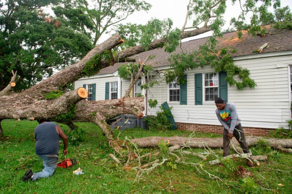 Workers cut apart a tree that fell on a home in Moss Point on Tuesday, June 20, 2023, after a tornado tore through the town on Monday.