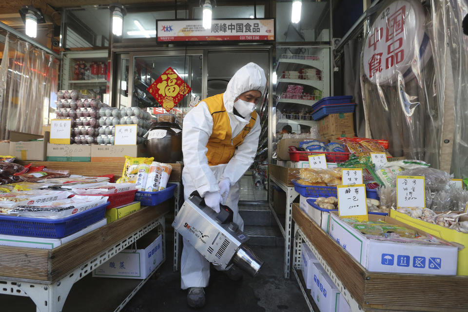 A worker wearing protective gears sprays disinfectant at a Chinese food store as a precaution against a new coronavirus at Daelim market in Seoul, South Korea, Wednesday, Feb. 5, 2020. Deaths from a new virus rose to 490 in mainland China on Wednesday while new cases on a Japanese cruise ship, in Hong Kong and in other places showed the increasing spread of the outbreak and renewed attention toward containing it. (AP Photo/Ahn Young-joon)