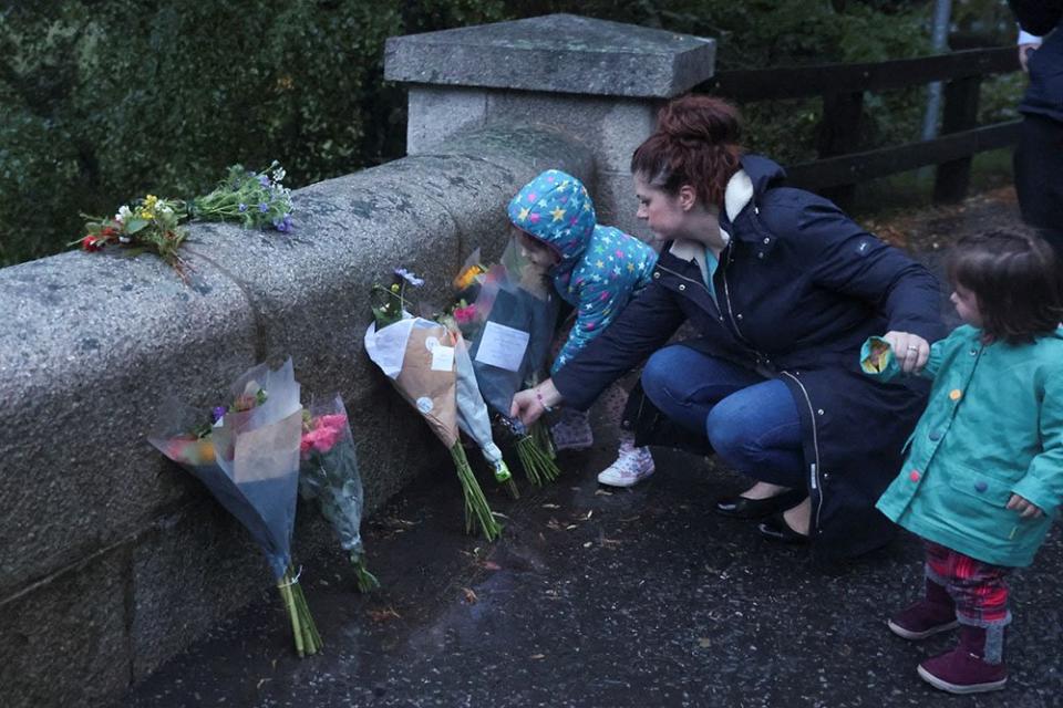 A woman places flowers by an entrance to Balmoral Castle