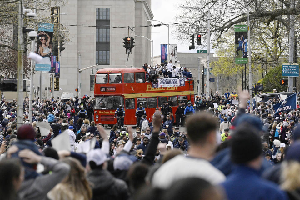 Fans surround a double-decker bus carrying the UConn men's basketball team during a parade to celebrate the team's NCAA college basketball championship, Saturday, April 13, 2024, in Hartford, Conn. (AP Photo/Jessica Hill)