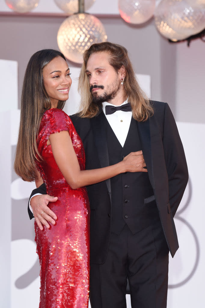 wearing a sparkly dress with cap sleeves, Zoe wraps her arms around Marco, who's wearing a classic tux, complete with a waistcoat