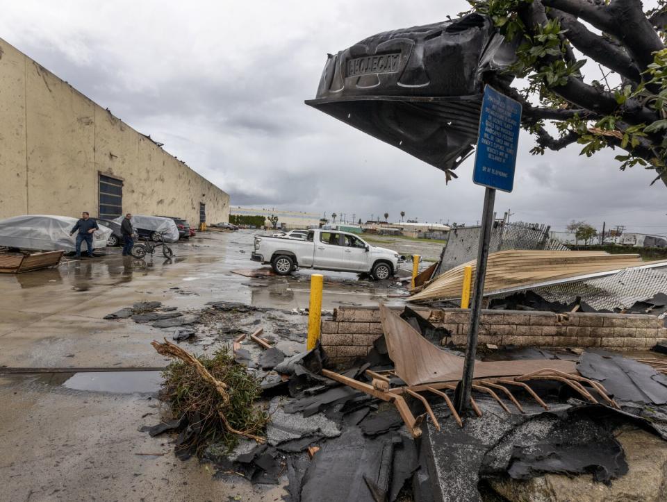 A pickup bed liner is lodged in a tree as employees view the damage in Montebello.