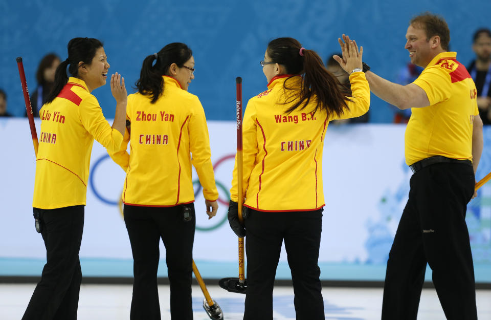 Team China coach Marcel Rocque of Canada congratulates his players, from left, Liu Yin, Zhou Yan and Wang Bingyu, on a good practice during the first day of curling training at the 2014 Winter Olympics, Saturday, Feb. 8, 2014, in Sochi, Russia. (AP Photo/Robert F. Bukaty)