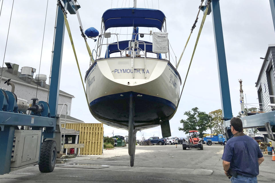 CORRECTS TO MARINA WORKER, INSTEAD OF BOAT OWNER A marina worker watches as a sailboat is hauled out of the water onto dry land in advance of an expected storm, Friday Aug. 20, 2021, in Plymouth, Mass. New Englanders, bracing for their first direct hit by a hurricane in 30 years, are taking precautions as Tropical Storm Henri barrels toward the southern New England coast. (AP Photo/Phil Marcelo)