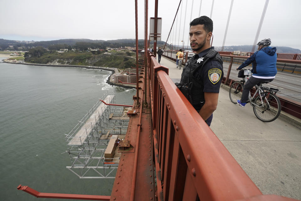 FILE - Patrol officer Nicolas Serrano looks out at a suicide barrier under construction below the Golden Gate Bridge in San Francisco on Aug. 3, 2021. The lead contractor in charge of building a suicide prevention net on San Francisco’s Golden Gate Bridge that is already years behind schedule says it will cost about $400 million, more than double its original price, because of deterioration that was concealed and other problems. (AP Photo/Eric Risberg, File)