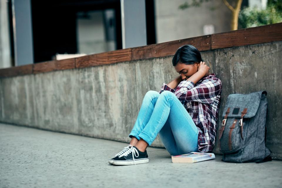 A stressed student sits along a wall