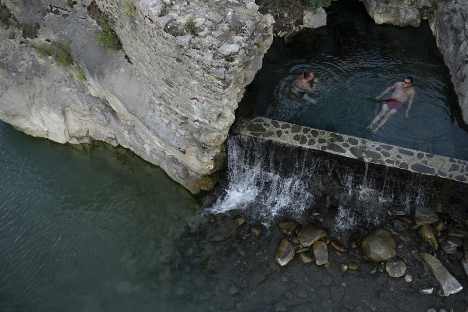 FILE - People bathe in a thermal spring on the banks of the Langarica River, a tributary to the Vjosa near Permet, Albania June 20, 2019. Albanian officials on Monday, June 13, 2022, declared the Vjosa River and its tributaries a future national park, a move aimed at preserving what they called one of the last wild rivers in Europe. The Albanian Ministry of Tourism and Environment signed an agreement with the California-based Patagonia environmental organization to draft an “integrated and sustainable plan" for the new park. (AP Photo/Felipe Dana, File)