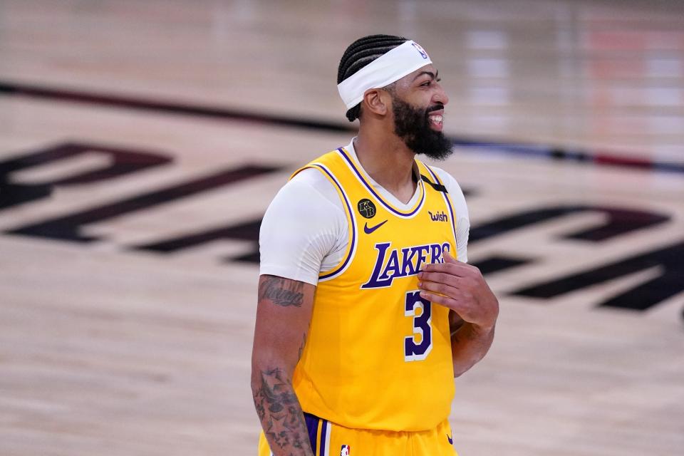 FILE - In this Friday, Sept. 18, 2020, file photo, Los Angeles Lakers forward Anthony Davis smiles as he stands on the court during the second half an NBA conference final playoff basketball game against the Denver Nuggets in Lake Buena Vista, Fla. The jerseys will be hanging in their lockers when the Los Angeles Lakers arrive for Game 2 of the NBA Finals on Friday night, Oct. 2. Black jerseys, trimmed in gold, a snakeskin print on the exterior to make it further unique.T hey are the Black Mamba jerseys. Designed by Kobe Bryant — and now worn for Kobe Bryant. “We never want to lose in these jerseys,” Lakers forward Anthony Davis said. (AP Photo/Mark J. Terrill, File)