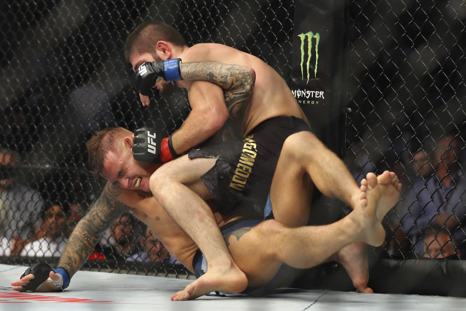 Russian UFC fighter Khabib Nurmagomedov, top, fights with UFC fighter Dustin Poirier, of Lafayette, La., during Lightweight title mixed martial arts bout at UFC 242, in Yas Mall in Abu Dhabi, United Arab Emirates, Saturday , Sept.7 2019. (AP Photo/ Mahmoud Khaled)