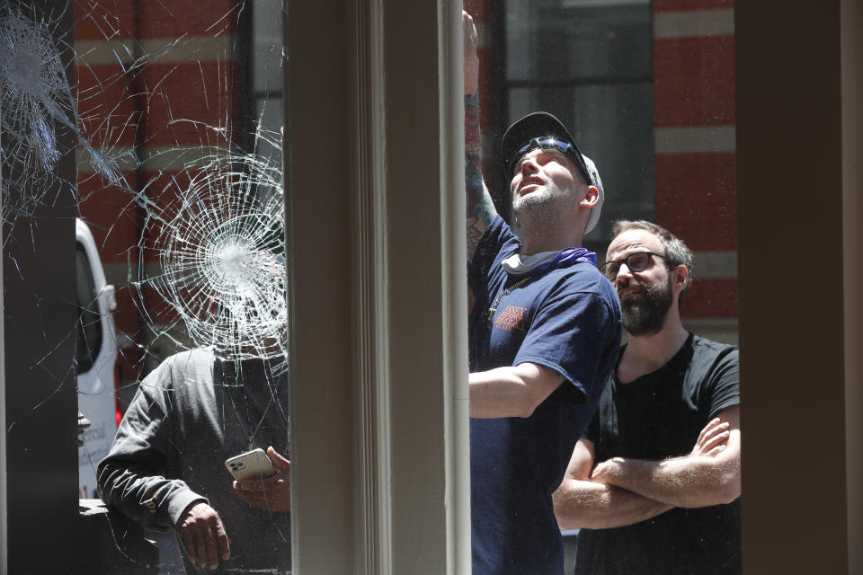 Nilas Porman, right, the manager of a Bang & Olufson store, watches as worker, center, describes how he will repair and protect the store's broken windows, Sunday, May 31, 2020, in New York. The windows were broken Saturday night during protests over the death of George Floyd, who died May 25 after he was pinned at the neck by a Minneapolis police officer. (AP Photo/Kathy Willens)