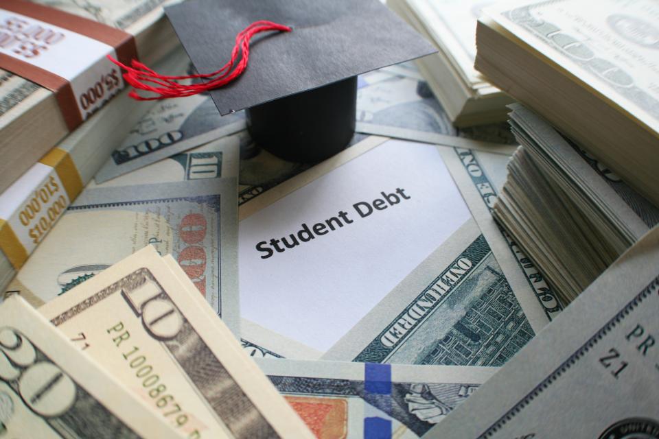 A piece of paper that says student debt surrounded by U,S. currency.