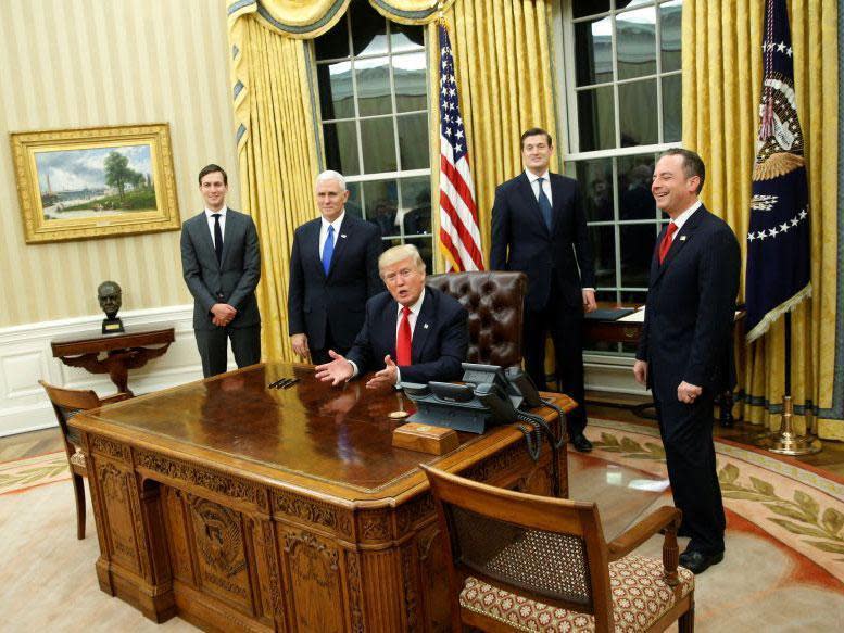 Donald Trump and his closest advisers sign the first orders of his presidency. Winston Churchill's bust can be seen in the background on the left: Reuters