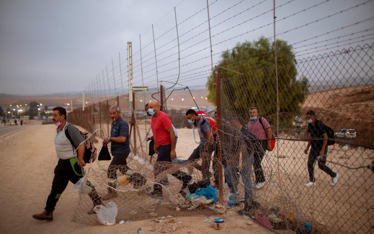 Palestinian labourers cross into Israel through a hole in a fence south of Hebron - AP