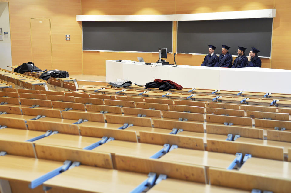 Examiners sit in an empty classroom as they listen to students defending their thesis on line, at the Politecnico University in Milan, Italy, Thursday, March 5, 2020. Italy's virus outbreak has been concentrated in the northern region of Lombardy, but fears over how the virus is spreading inside and outside the country have prompted the government to close all schools and Universities nationwide for two weeks. (Gian Luigi D'Alberto/LaPresse via AP)