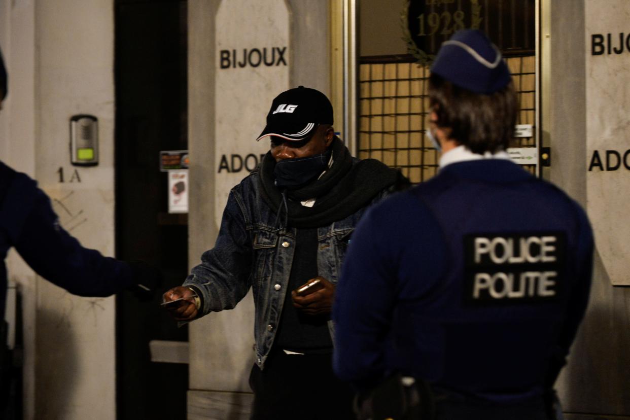 Police officers check the documents of a man while patrolling in central Brussels during a curfew imposed by the Belgian government (REUTERS)