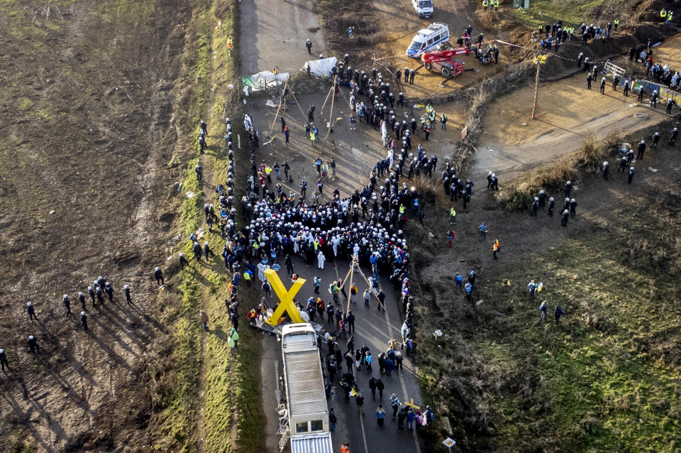 Police officers and demonstrators meet on a road at the village Luetzerath near Erkelenz, Germany, Tuesday, Jan. 10, 2023. The village of Luetzerath is occupied by climate activists fighting against the demolishing of the village to expand the Garzweiler lignite coal mine near the Dutch border. (AP Photo/Michael Probst)