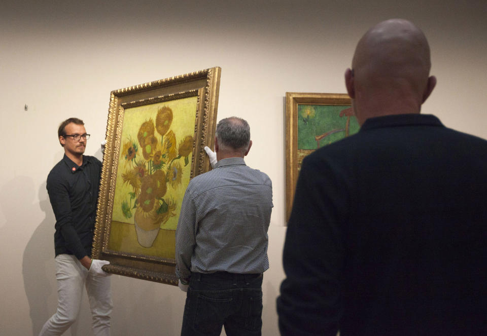 Curators remove Vincent van Gogh's famous "Sunflowers" painting from the wall of the Van Gogh Museum in Amsterdam, Netherlands, Sunday, Sept. 23, 2012. While the museum closes for seven months for renovations, 75 works by the Dutch painter will be displayed instead across town at The Hermitage, an Amsterdam satellite of the Russian state museum. The tricky process of transporting the artworks under police escort began immediately after the last visitors left the museum Sunday evening and carried on through the night into Monday morning. The Van Gogh Museum reopens April 25, 2013. (AP Photo/Cris Toala Olivares)