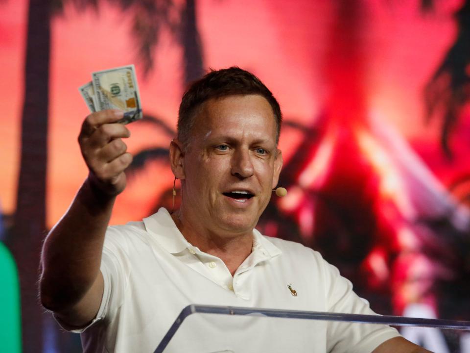 Peter Thiel, co-founder of PayPal, Palantir Technologies, and Founders Fund, holds hundred dollar bills as he speaks during the Bitcoin 2022 Conference at Miami Beach Convention Center on April 7, 2022 in Miami, Florida. 