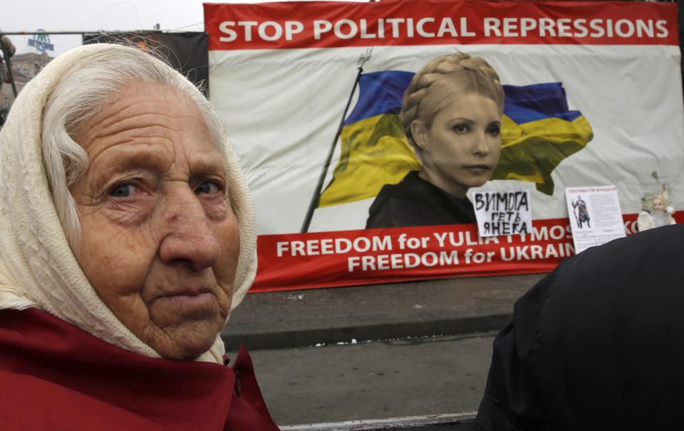 A woman looks on in front of a poster showing jailed Ukrainian opposition leader Tymoshenko in central Kiev