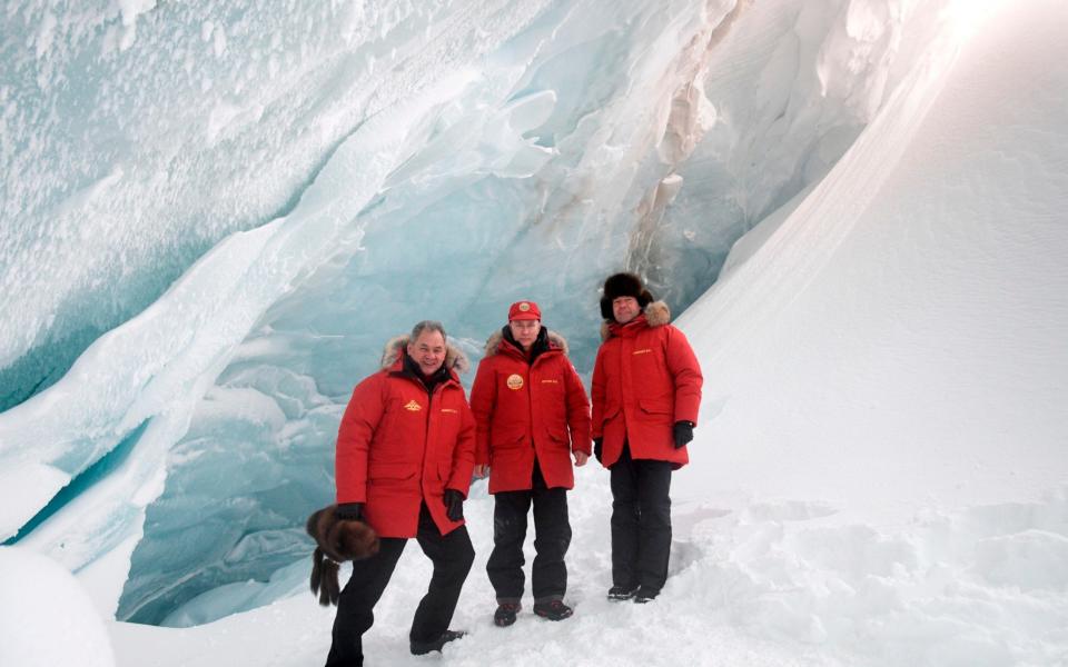 Russian President Vladimir Putin, Prime Minister Dmitry Medvedev, and Defense Minister Sergei Shoigu pose for a photo as they inspect a cavity in a glacier on the Arctic Franz Josef Land archipelago in Arctic Russia - Credit: Pool Sputnik Kremlin/AP