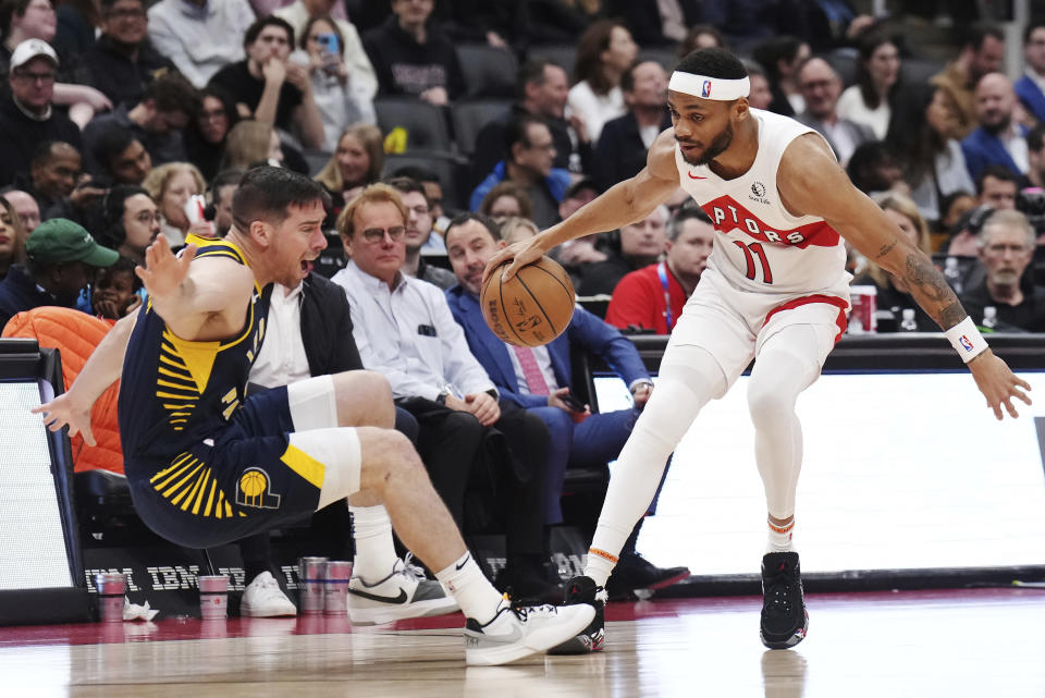 Indiana Pacers guard T.J. McConnell, left, stumbles as Toronto Raptors forward Bruce Brown (11) controls the ball during the second half of an NBA basketball game in Toronto on Tuesday, April 9, 2024. (Nathan Denette/The Canadian Press via AP)