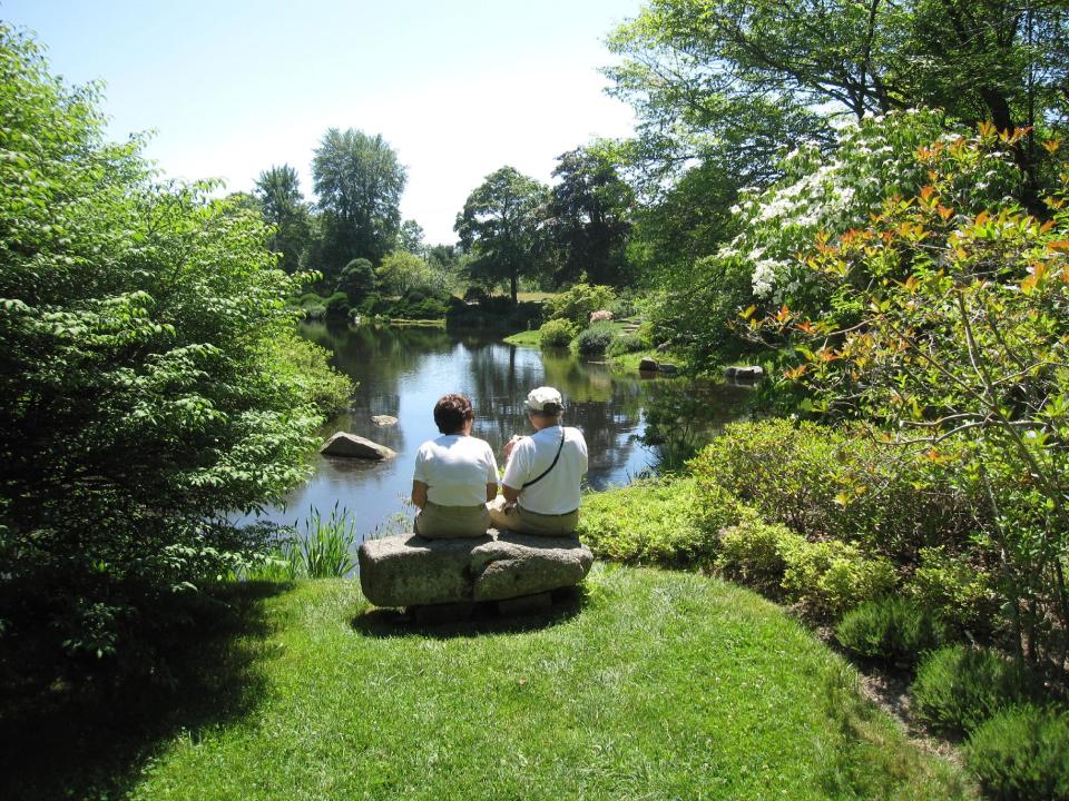 In this July 12, 2012 photo, visitors sit on a rock bench to view the scenery at the Asticou Azalea Garden pond in Northeast Harbor, Maine. The garden includes plants from the collection of renowned landscape designer Beatrix Farrand, who has connections to several gardens in the area, including the nearby Abby Aldrich Rockefeller Garden, a private garden that’s only open to the public a few days a year. (AP Photo/Beth J. Harpaz)