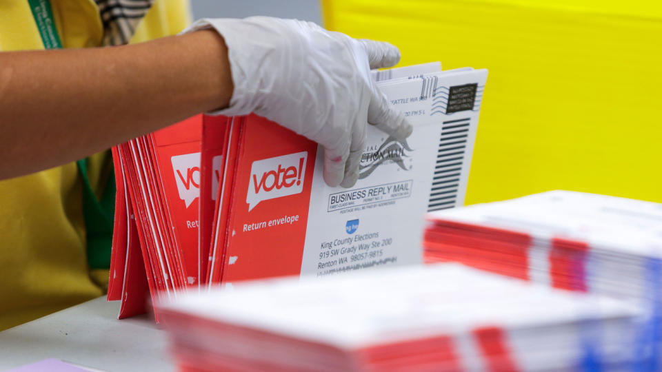 An election worker opens envelopes containing vote-by-mail ballots