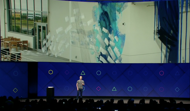 Zuckerberg stands under a slide of a wall with augmented reality graffiti.