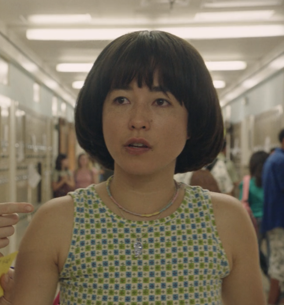 Maya in a scene with a brightly colored tanktop, necklace, and hair in a bob