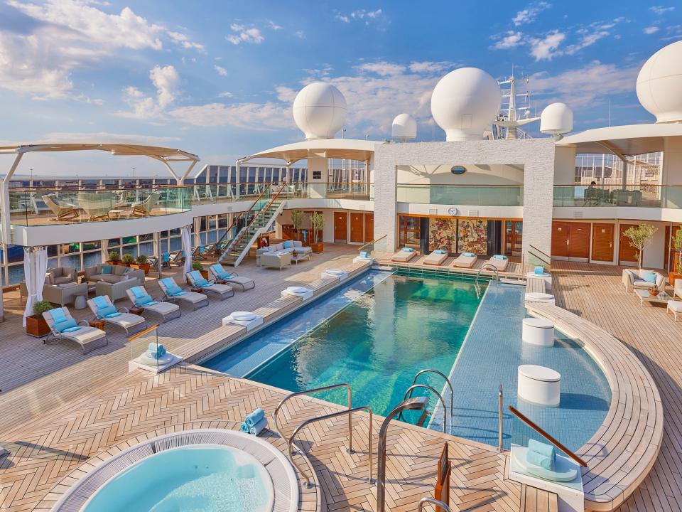 The pool deck on The World, featuring a large pool, sun loungers, and a hot tub.