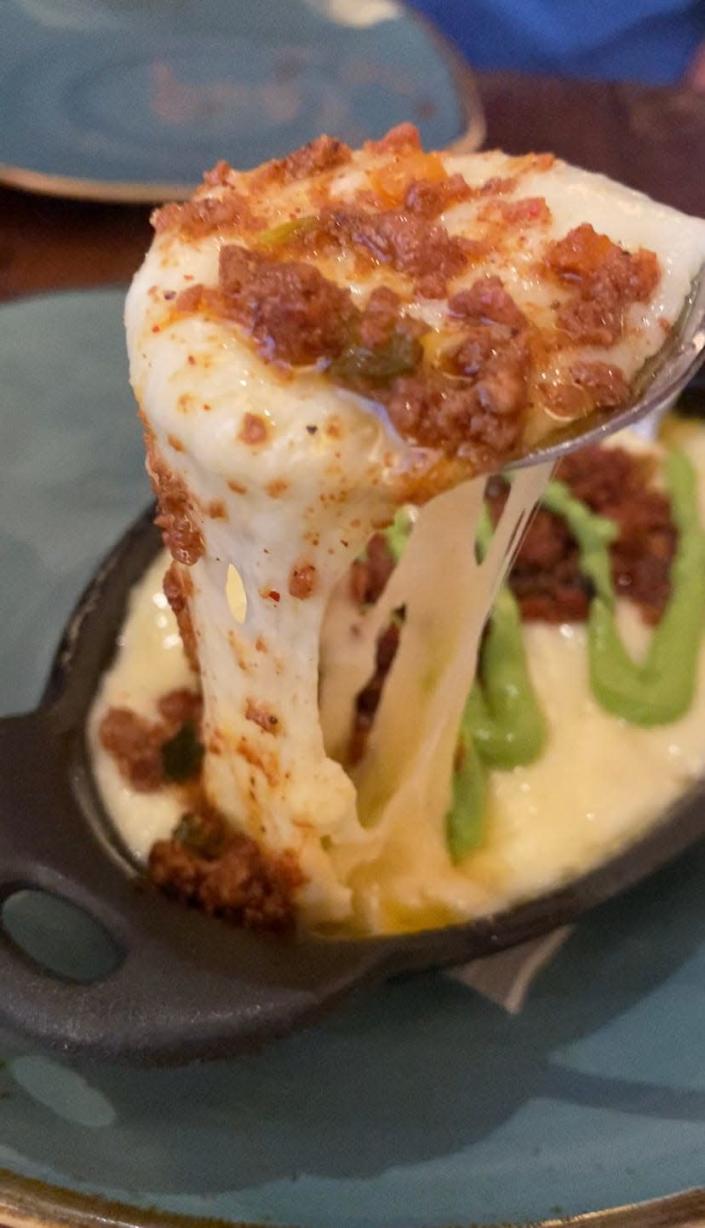 spoon pulling cheese from bowl of queso fundido at mexico restaurant at epcot