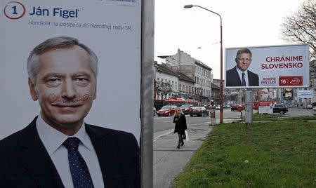 A woman walks past election posters showing candidates of Smer party and Slovakia's Prime Minister Robert Fico (R) and KDH party Jan Figel in Bratislava, Slovakia, March 4, 2016. The poster on the right reads: "We protect Slovakia" REUTERS/David W Cerny