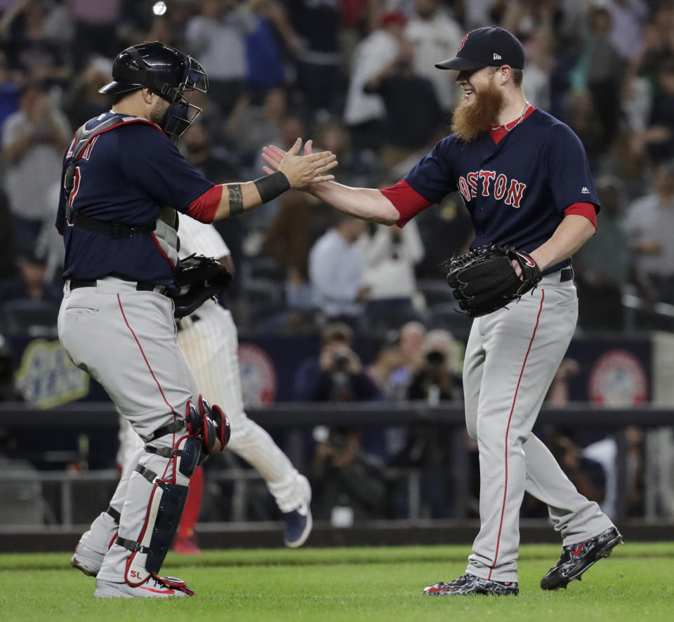 Boston Red Sox relief pitcher Craig Kimbrel, right, and catcher Sandy Leon celebrate after defeating the New York Yankees 11-6 during a baseball game, Thursday, Sept. 20, 2018, in New York. With the win, the Red Sox clinched the American League East Division title. (AP Photo/Julio Cortez)