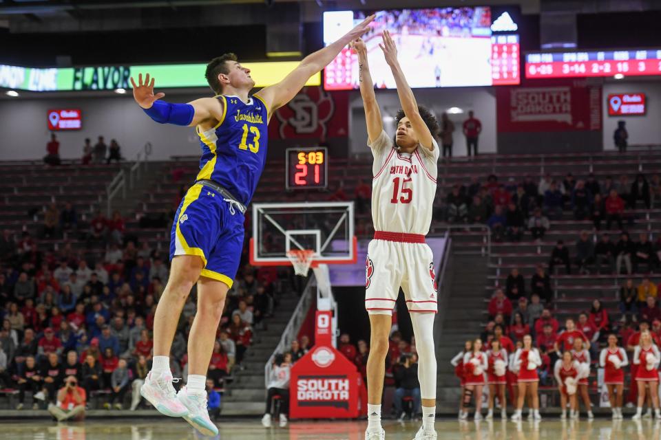 South Dakota forward Jevon Hill (15) attempts a 3-pointer while being contested by Luke Appel (13) on Saturday, Jan. 20, 2024 at Sanford Coyote Sports Center in Vermillion.