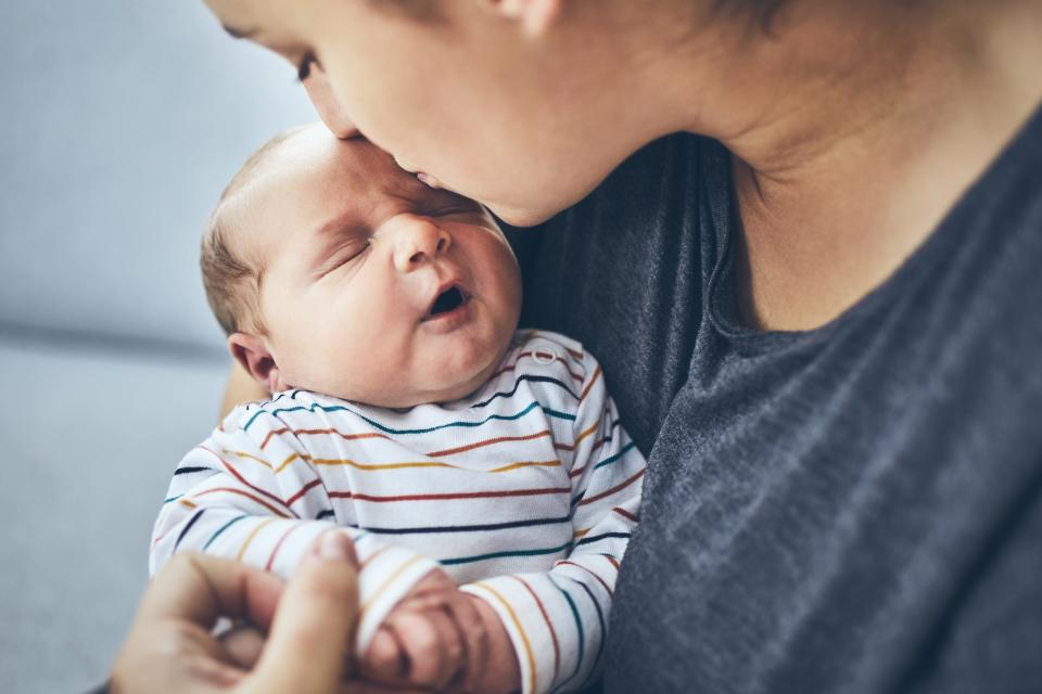 Mother with newborn. Woman kissing her 4 days old son at home.