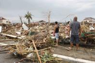 Survivors assess the damage after super Typhoon Haiyan battered Tacloban city, central Philippines November 9, 2013. Typhoon Haiyan, the strongest typhoon in the world this year and possibly the most powerful ever to hit land battered the central Philippines on Friday, forcing millions of people to flee to safer ground, cutting power lines and blowing apart houses. Haiyan, a category-5 super typhoon, bore down on the northern tip of Cebu Province, a popular tourist destination with the country's second-largest city, after lashing the islands of Leyte and Samar with 275 kph (170 mph) wind gusts and 5-6 meter (15-19 ft) waves. REUTERS/Romeo Ranoco (PHILIPPINES - Tags: DISASTER ENVIRONMENT)