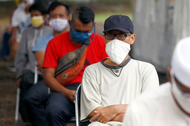 FILE PHOTO: People wearing protective face mask practice social distancing while receiving rice from an automated rice ATM distributor amid the coronavirus disease (COVID-19) spread in Jakarta