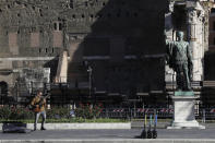 A street musician performs with his electric guitar beside the statue of Roman Emperor Julius Cesar on a almost empty Via Dei FOri Imperiali avenue in Rome, Wednesday, Oct. 28, 2020. Italy on Tuesday registered nearly 22,000 confirmed COVID-19 infections since the previous day, its highest one-day total so far in the pandemic. The day-to-day increase in confirmed deaths also jumped, to 221, according to Health Ministry figures. (AP Photo/Gregorio Borgia)