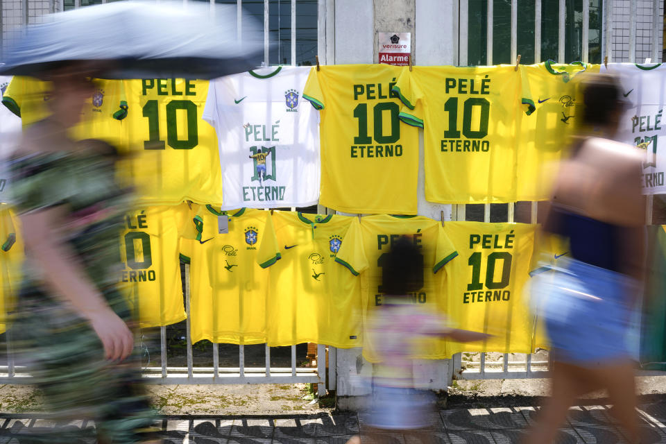 Jerseys for sale featuring the player number and name of Pele hang where people walk to the Vila Belmiro stadium where the late Brazilian soccer great lies in state in Santos, Brazil, Monday, Jan. 2, 2023. (AP Photo/Matias Delacroix)