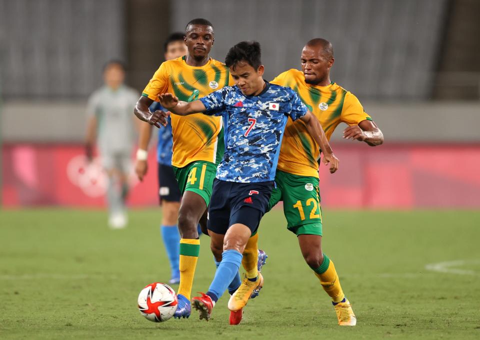 Takefusa Kubo of Team Japan is challenged by Goodman Mosele of Team South Aftrica during the Men's First Round Group A match between Japan and South Africa during the Tokyo 2020 Olympic Games at Tokyo Stadium on July 22, 2021 in Chofu, Tokyo, Japan.