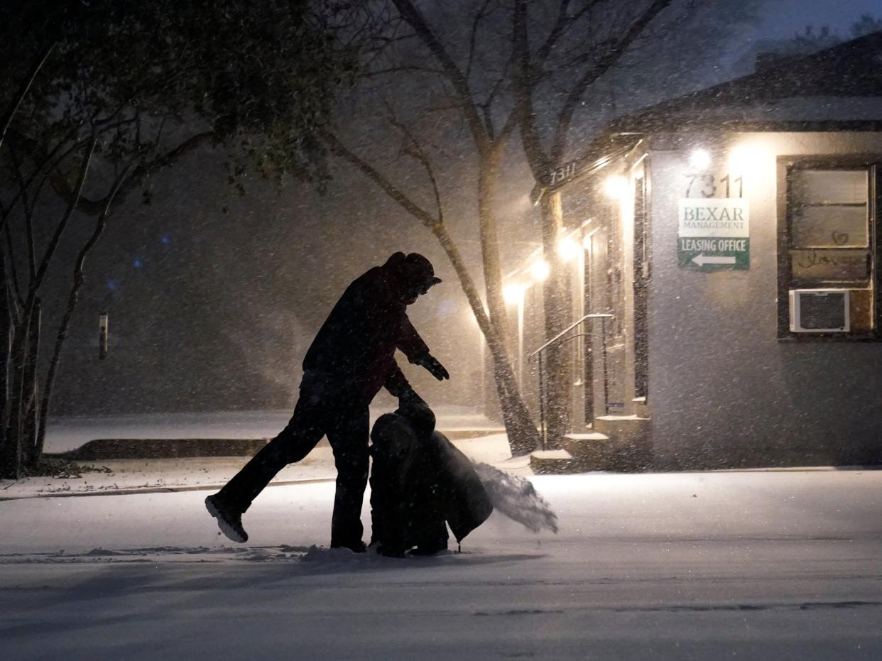 <p>Two people play in the snow in San Antonio, on 14 February 2021</p> ((Associated Press))