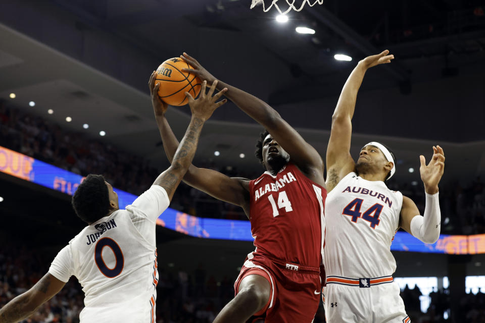 Alabama center Charles Bediako (14) is fouled by Auburn guard K.D. Johnson (0) as he goes up for a shot with center Dylan Cardwell (44) defending during the first half of an NCAA college basketball game, Saturday, Feb. 11, 2023, in Auburn, Ala. (AP Photo/Butch Dill)