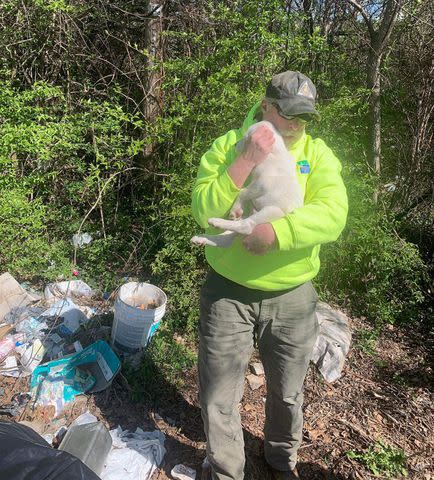 <p>Missouri Dept. of Conservation</p> A clean-up crew worker holding the puppy he pulled from a garbage pile