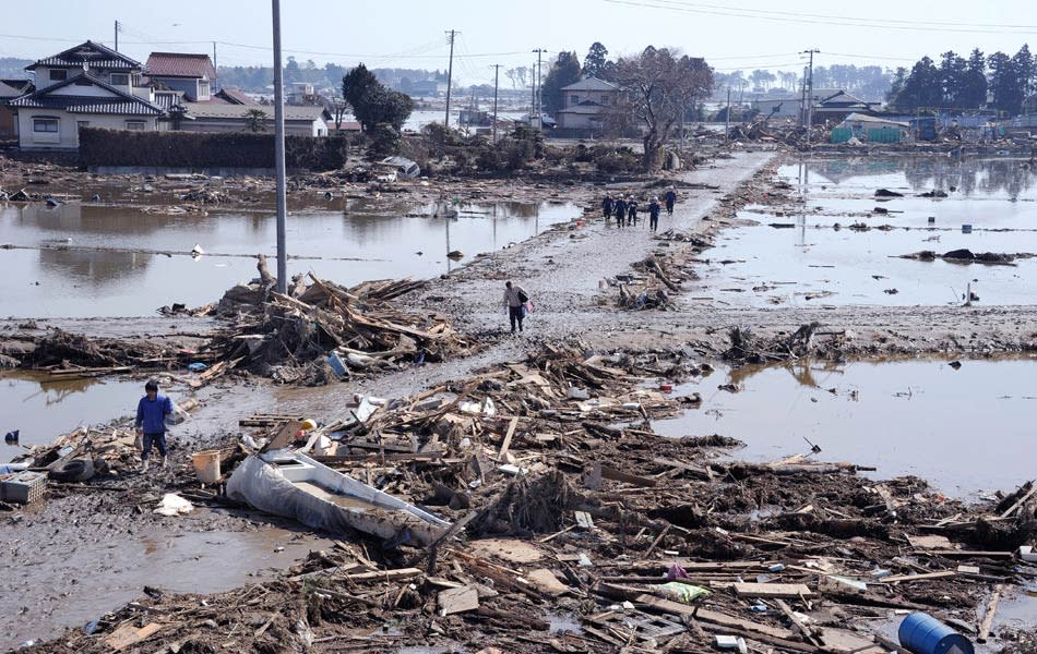 Residents walking on roads covered with mud and debris in a tsunami hit area of Sendai, Miyagi Prefecture, on March 14, 2011.AFP PHOTO / TORU YAMANAKA