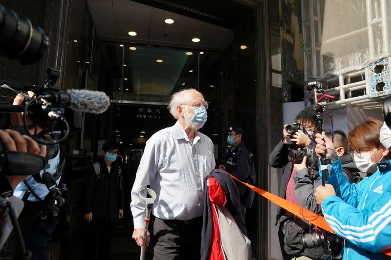 American lawyer John Clancey walks out of a building as he is taken away by police officers in Hong Kong