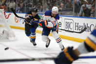 Edmonton Oilers' Mattias Ekholm (14) passes as St. Louis Blues' Alexey Toropchenko (13) defends during the second period of an NHL hockey game Monday, April 1, 2024, in St. Louis. (AP Photo/Jeff Roberson)