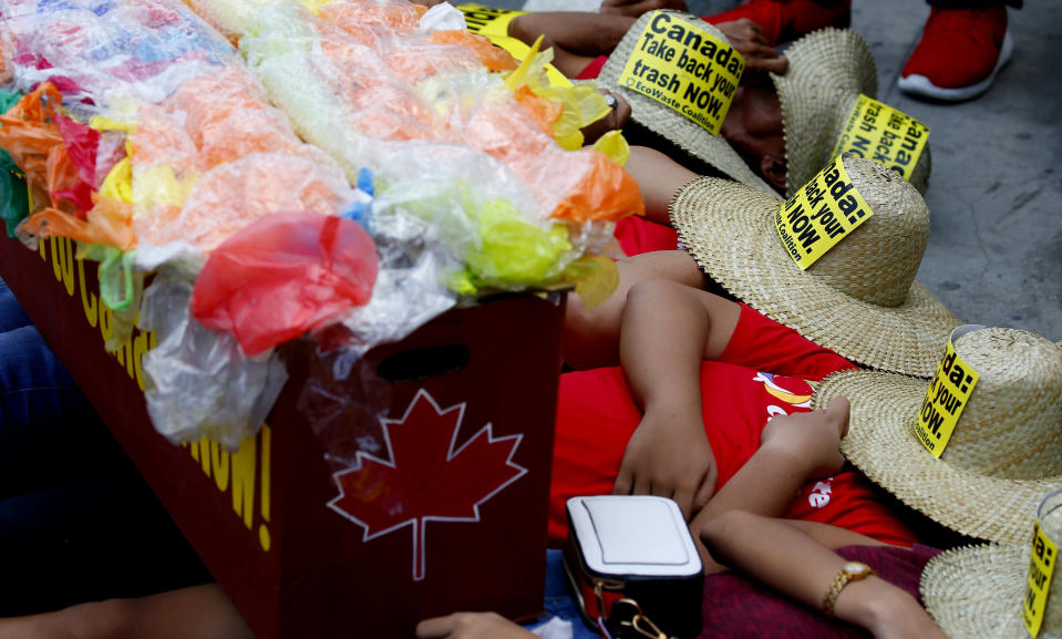 With a mock container loaded with garbage, environmentalists stage a die-in protest outside the Canadian Embassy to demand the Canadian government to speed up the removal of several containers of garbage that were shipped to the country Tuesday, May 21, 2019, in Manila, Philippines. The Philippines recalled its ambassador and consuls in Canada last week over Ottawa's failure to comply with a deadline to take back 69 containers of garbage that Filipino officials say were illegally shipped to the Philippines years ago. (AP Photo/Bullit Marquez)