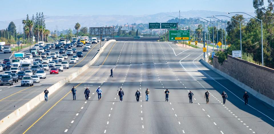 Police investigators walk along the closed northbound lanes of the 55 freeway south of Chapman Avenue looking for evidence after a shooting May 21 in Orange, Calif. A 6-year-old boy seated in the backseat of his mother’s car was shot to death by another motorist, authorities said.