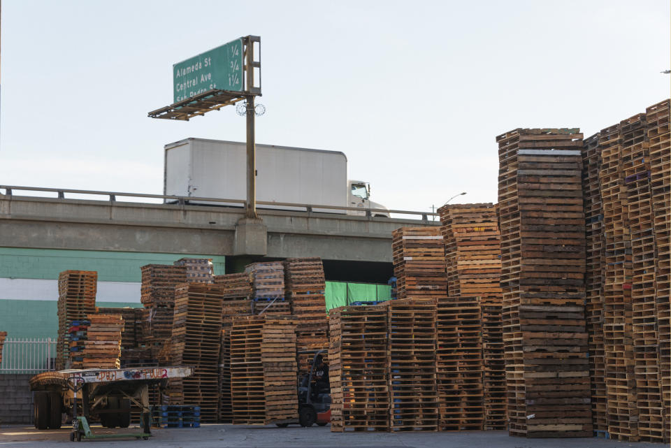 Wooden pallets are stored on a property adjacent to the Interstate 10 in Los Angeles, Thursday, Dec. 7, 2023. (AP Photo/Damian Dovarganes)